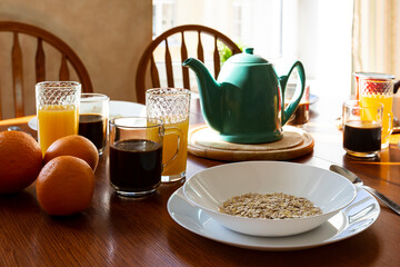 Served morning b&b breakfast on a table: muestli, orange juice, oranges and black coffee
