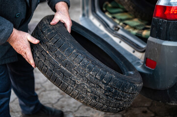 man unloads a set of change tires from the trunk, seasonal tire change concept, close-up