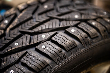 close-up of snow tire with metal studs, which improve traction on icy surfaces, studded winter tyre