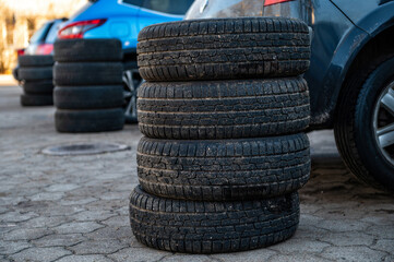 winter tires next to the car in wheel service, seasonal tire change concept, close-up