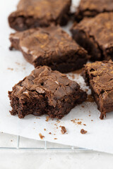Chocolate brownies slices on baking paper and rack with crumbles on concrete table.