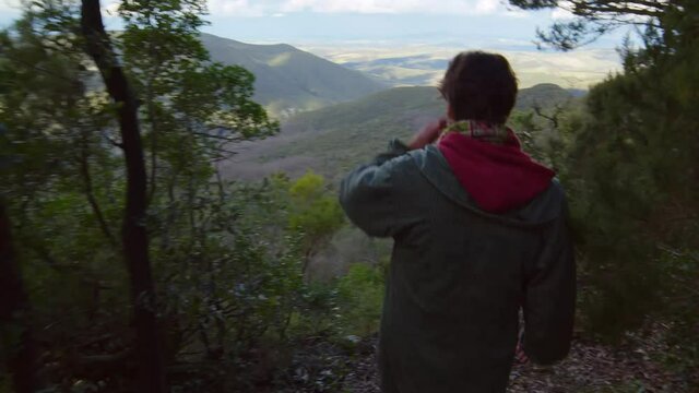 Un escursionista fotografa una vallata dalla cima di un monte boscoso