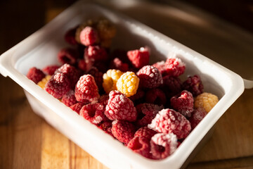 Close view of frozen red and yellow raspberry berries in a box
