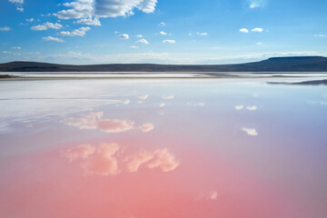 Salt lake with pink water . The cloudy sky is reflected in the water. Shooting from a drone. Copy space.