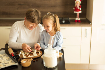 Girls with grandma are preparing Christmas cookies in the kitchen