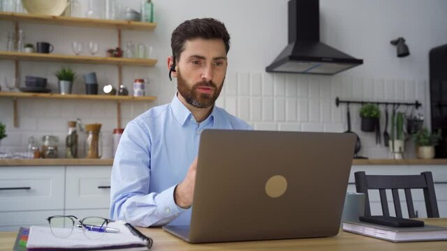 Smiling businessman webinar speaker in headset looking at camera webcam view