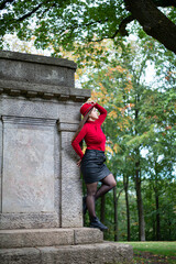 White woman with long dark hair in bright red near monument in park