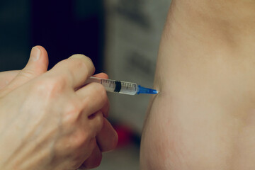 Injection with a syringe into the body. Self-medication at home. Medical disposable syringe with vaccine in hands without gloves.