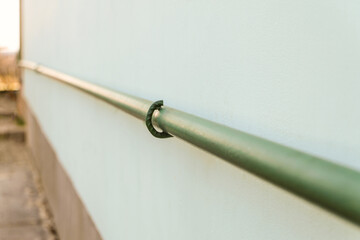 Metal gas pipe attached to the wall of a residential building. Limited depth of field.