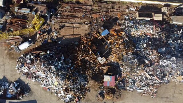 Aerial view of machineries working at scrap metal recycling yard. Cranes move metal to compactor. Metal recycling industrial area