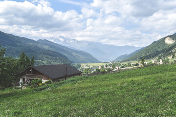 View of highland townlet Mestia in Svaneti region, Georgia. Green meadows, valles and rural houses. Caucasus mountain range, snow capped mountains in the background