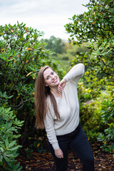 Smiling white european woman in white sweater within trees