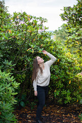 White european woman in white sweater with trees behind