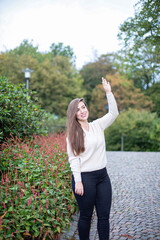 White european woman in white sweater and black jeans in park