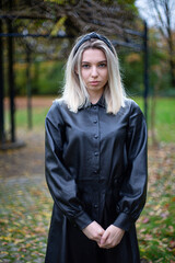Young european white girl with blonde hair in park dressed in black in park