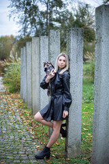 White young european woman with blonde hair with a small dog near concrete pillars