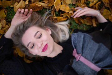 Smiling young european white girl with blonde hair portrait in fall foliage