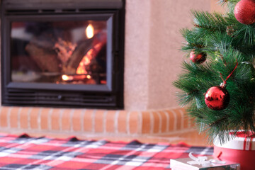 Christmas tree with red balls and fireplace in background