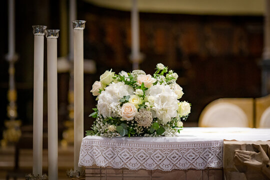 White wedding bouquet on stand in church surrounded by candles on wedding ceremony