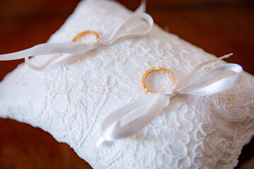 Close up pair of two golden wedding rings seton white decorative cushion for bride and groom
