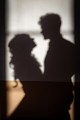 Shadows on wall of two lovers bride and groom hug and look to each other