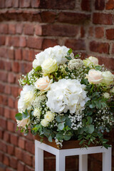 Beautiful white yellow flower bouquet stand on chair with brown brick wall background