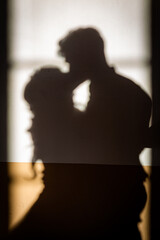 Vertical view shadows on white wall couple of young caucAsian unrecognizable lovers kiss each other