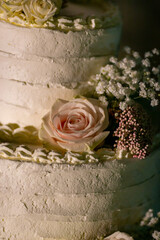 Macro view decoration of real natural rose on side of white wedding cake