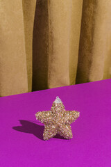Retro vintage scene with a golden Christmas decorative star on a purple background against a golden curtain. Creative luxury Christmas party.