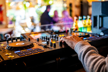 dj hand manipulating the controls of a mixing console in nightclub