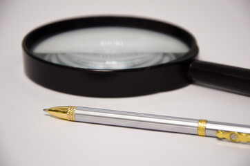 magnifier and pen lies on a white background. office supplies. office items
