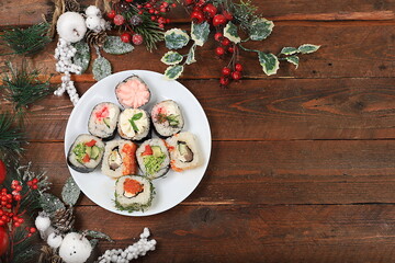 Fresh sushi rolls herringbone with sauce on wooden background with holiday decorations, christmas new year food, traditional japanese cuisine, banner for shop advertisement or invitation