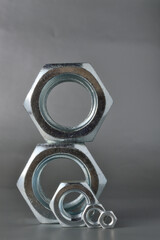 composition of new bolts and nuts of different sizes on a gray background.