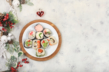 Herringbone of fresh sushi rolls with sauce on a light background with holiday decorations, christmas new year food, traditional japanese cuisine, banner for shop advertisement or invitation,