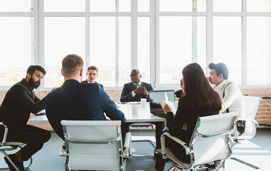 Group of young business people working and communicating while sitting at the office desk together...