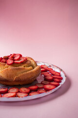 Cake with some strawberry slices on a pink background