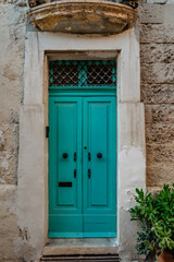 Fototapeta na wymiar Malta is home to amazingly unique doors.Traditional colorful Maltese door in Valletta.Front door to house from Malta.Blue turquoise wooden door and stone facade.Maltese vintage apartment building.