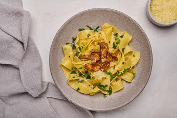 Close up Italian pasta pappardelle with mushrooms chanterelles, cheese and parsley on plate and napkin. Top view