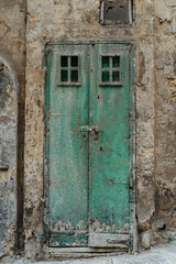 Malta is home to amazingly unique doors.Traditional old Maltese door in Valletta.Front door to house from Malta.Blue green antique wooden door and stone facade.Maltese vintage apartment building.