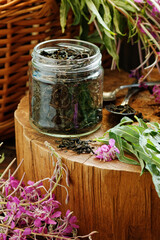 Willow herb tea, fermented herbal dry tea in glass jar with fresh flowers close on wooden rustic background, traditional russian hot drink, closeup, naturopathy and natural medicine concept