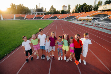 A large group of children, boys and girls, rejoice together and wave their hands at the stadium during the sunset post game. A healthy lifestyle.