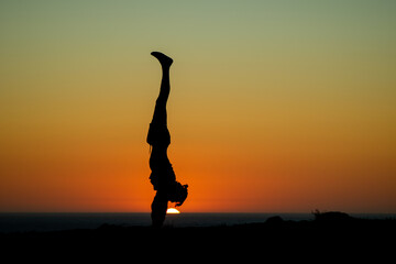 silhouette of a person in the sunset doing a handstand