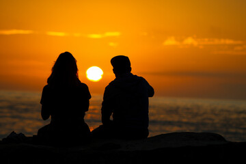 silhouette of a couple on the beach watching sunset