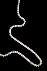White pearls on the black silk as background