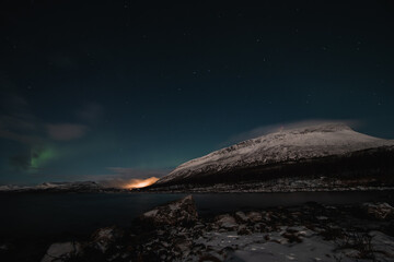 Borealis aurora sweeps over a large lake on a cloudless night in Kilpisjarvi, Lapland, Finland. aurora polaris in green dances across the sky. Scandinavian magic. Saana mountain in fog