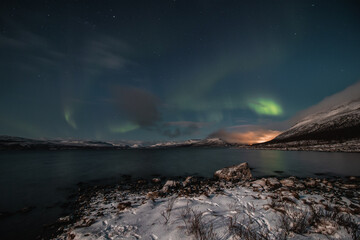 Borealis aurora sweeps over a large lake on a cloudless night in Kilpisjarvi, Lapland, Finland. aurora polaris in green dances across the sky. Scandinavian magic. Saana mountain in fog