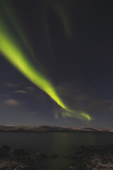 Borealis aurora sweeps over a large lake on a cloudless night in Kilpisjarvi, Lapland, Finland. aurora polaris in green dances across the sky. Scandinavian magic