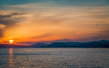 Silhouetted bird flies towards the dramatic sunset from the coastal town of Trogir, Croatia.