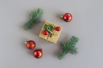 Craft gift box with spruce branch and red balls on a grey background. Holiday concept.
