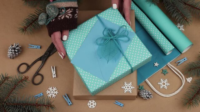 Woman packing Christmas gifts with blue paper p2